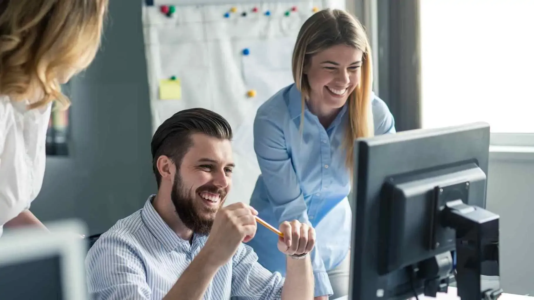 Team collaborating happily at computer workspace