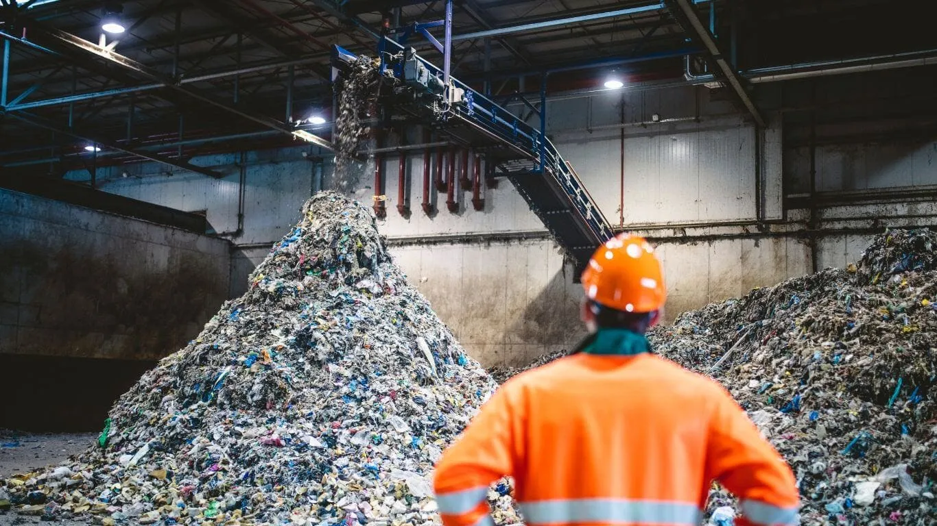 Worker observing waste pile in recycling facility