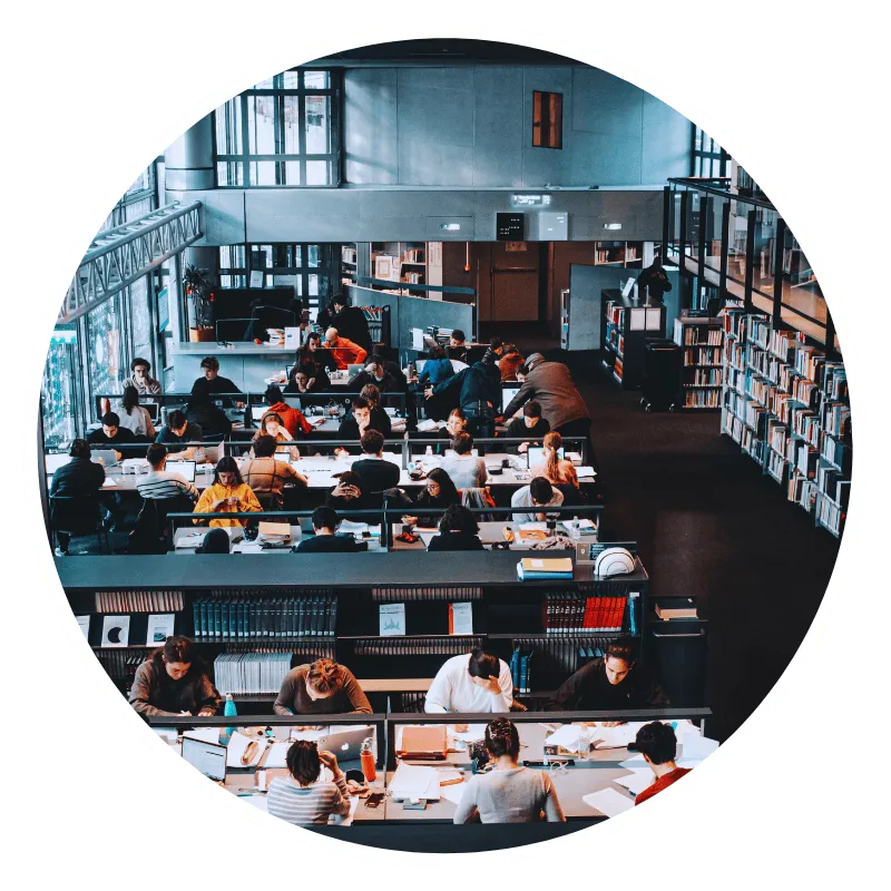 Students studying in a large, busy library.