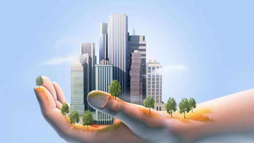 Hand holding miniature cityscape and trees.