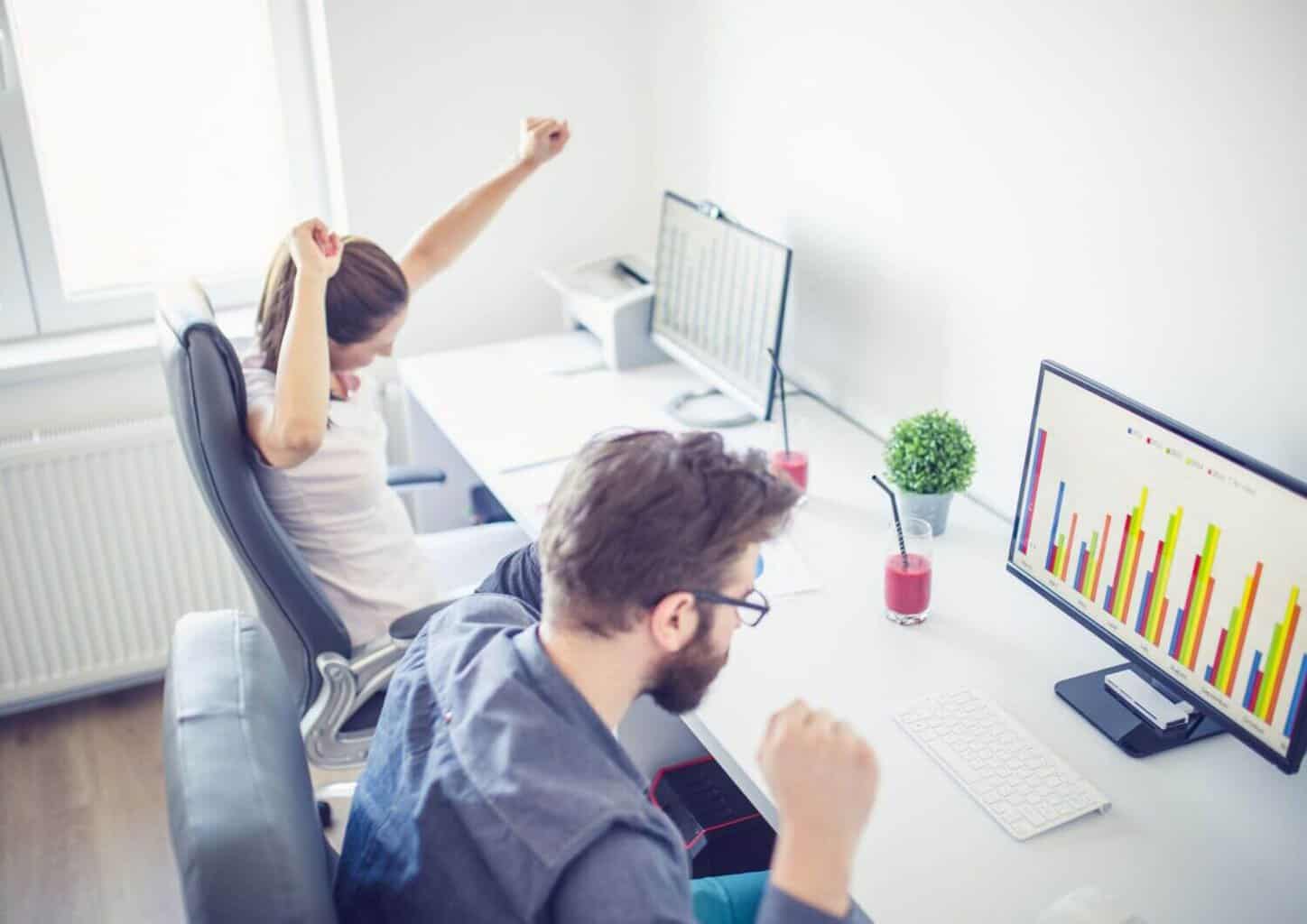 Two people celebrating success with business charts.