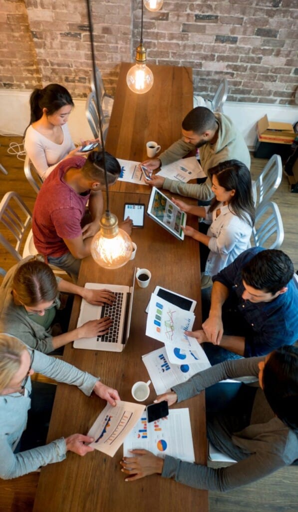 Group collaborating with laptops and charts on table
