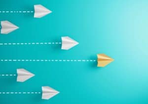 Paper planes flying, one yellow leading